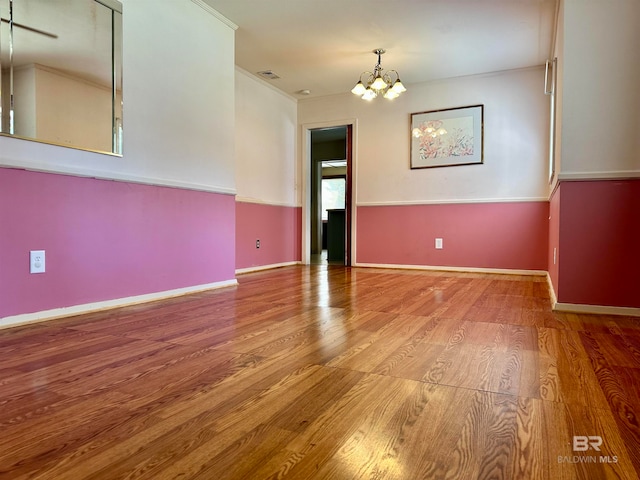 spare room featuring a chandelier and hardwood / wood-style floors