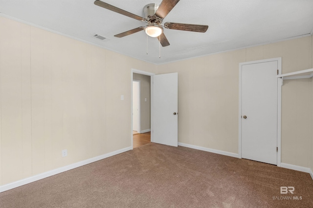 unfurnished bedroom featuring a closet, light colored carpet, ceiling fan, and crown molding