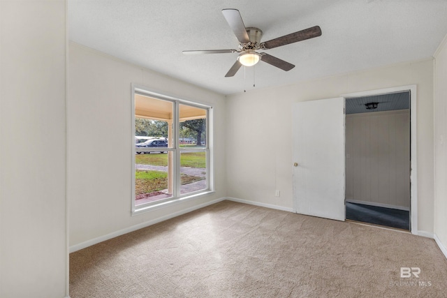 unfurnished room with ceiling fan, light colored carpet, and a textured ceiling