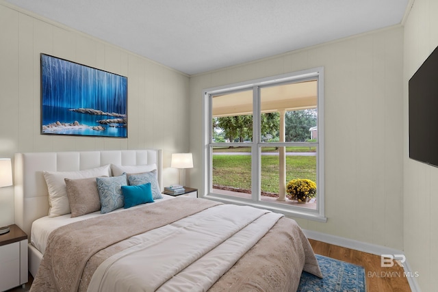 bedroom with crown molding, hardwood / wood-style floors, and wood walls