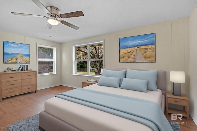 bedroom featuring ceiling fan, light hardwood / wood-style flooring, and a textured ceiling