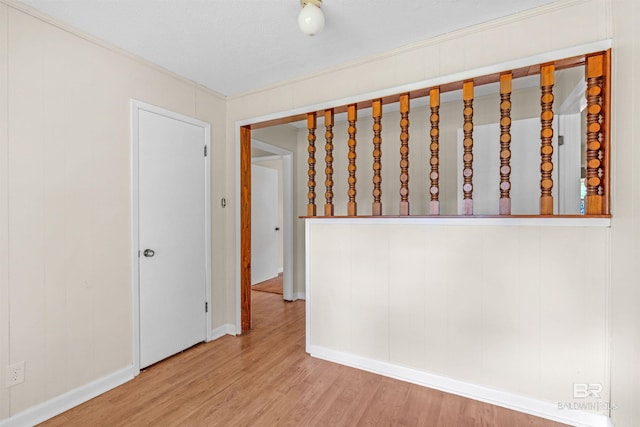 spare room featuring light wood-type flooring and crown molding