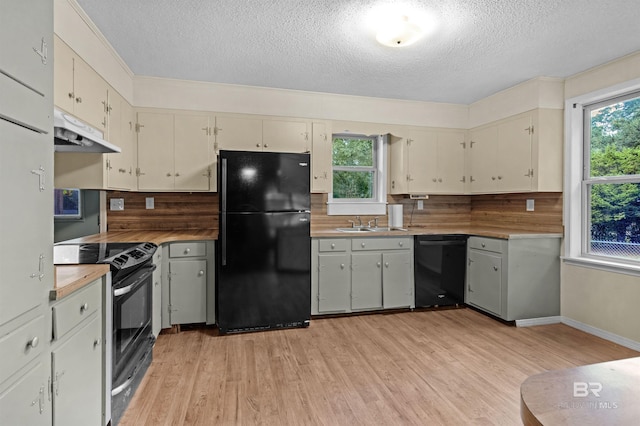 kitchen featuring black appliances, decorative backsplash, light wood-type flooring, and a textured ceiling