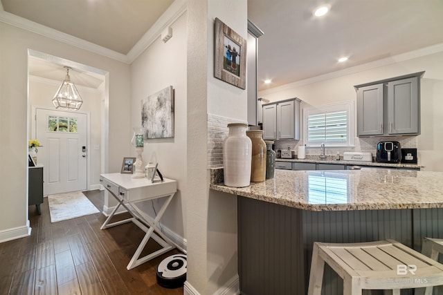 kitchen featuring light stone counters, dark wood-type flooring, ornamental molding, backsplash, and gray cabinets