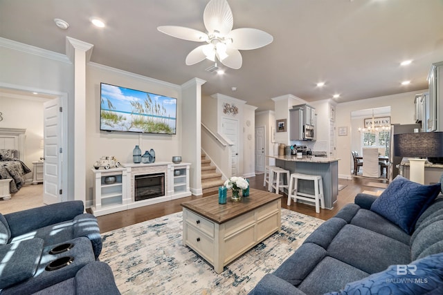 living area featuring a fireplace, recessed lighting, stairway, ornamental molding, and light wood-type flooring