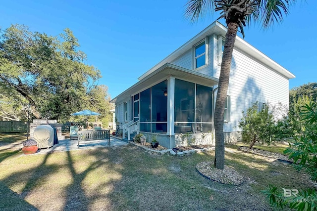 view of home's exterior with a sunroom, fence, a lawn, and a patio