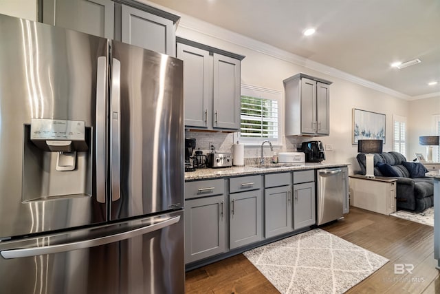 kitchen featuring crown molding, gray cabinets, appliances with stainless steel finishes, dark wood-type flooring, and open floor plan