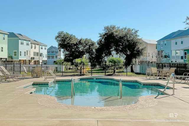 community pool featuring a residential view, fence, and a patio