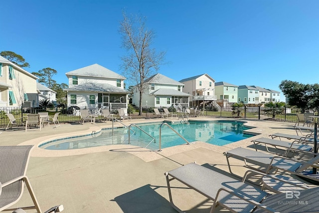 community pool featuring a patio, fence, and a residential view