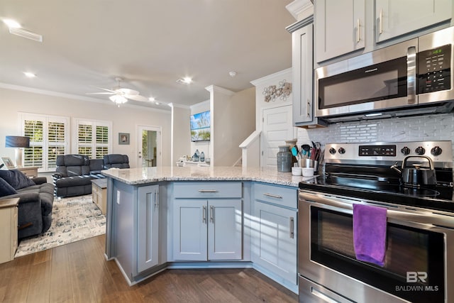 kitchen with stainless steel appliances, a peninsula, ornamental molding, backsplash, and dark wood-style floors