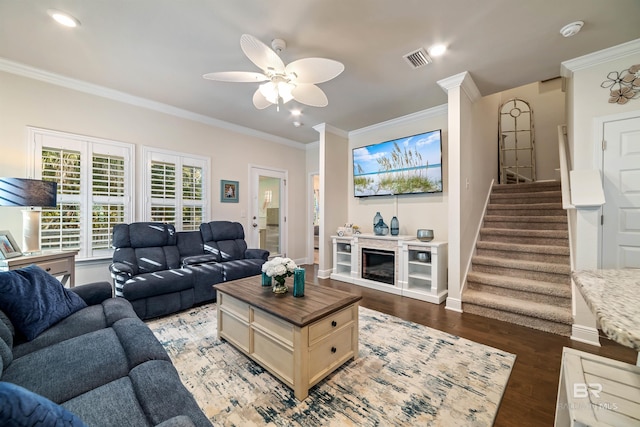 living area featuring baseboards, visible vents, wood finished floors, stairs, and crown molding