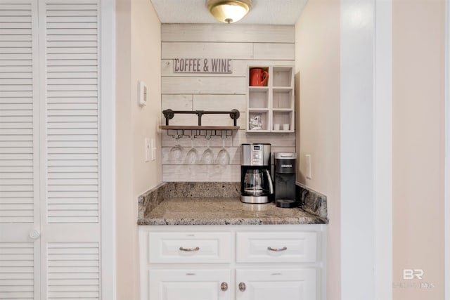 kitchen featuring white cabinets, light stone counters, and a textured ceiling