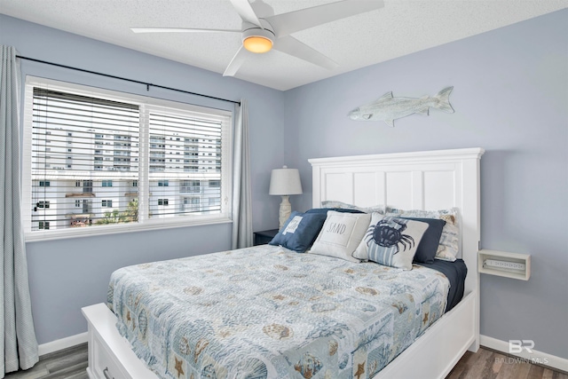 bedroom featuring dark hardwood / wood-style floors, ceiling fan, multiple windows, and a textured ceiling