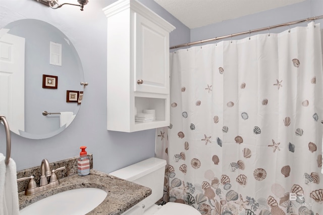 bathroom featuring vanity, toilet, and a textured ceiling