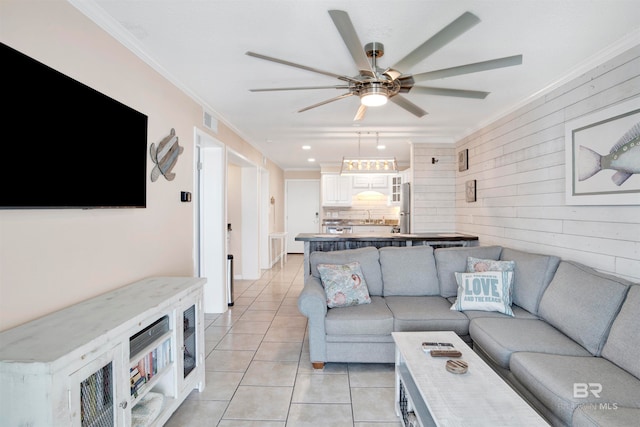 living room with crown molding, ceiling fan, and light tile floors