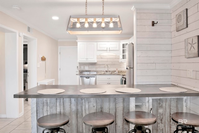 kitchen featuring a kitchen breakfast bar, crown molding, sink, white cabinets, and appliances with stainless steel finishes