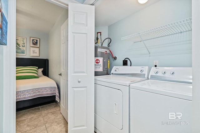 laundry room featuring water heater, washing machine and dryer, and light tile patterned floors