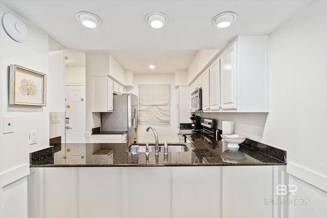 kitchen with dark stone countertops, appliances with stainless steel finishes, sink, and white cabinets