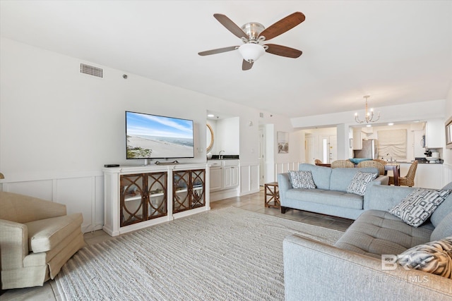 living room featuring sink and ceiling fan with notable chandelier