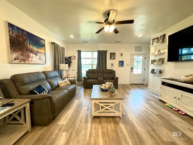 living room featuring light wood-type flooring, ceiling fan, and a healthy amount of sunlight