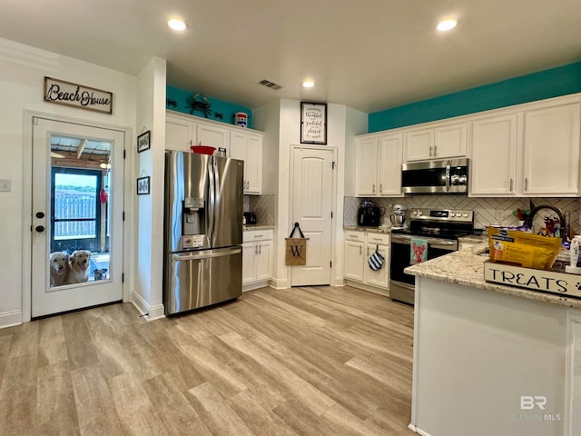 kitchen featuring appliances with stainless steel finishes, light hardwood / wood-style flooring, white cabinetry, and decorative backsplash