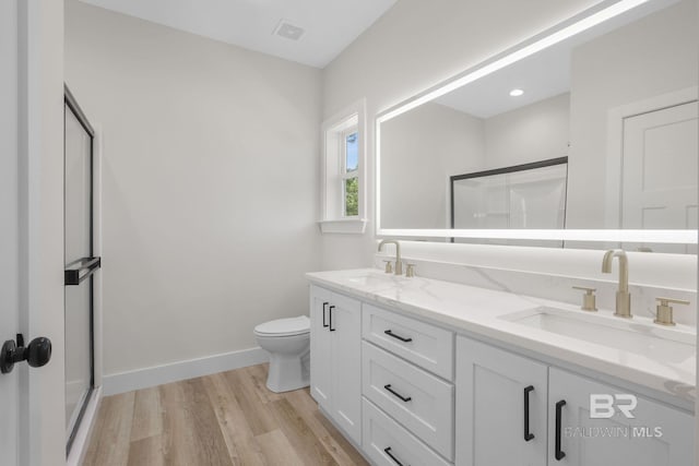 bathroom with hardwood / wood-style flooring, vanity, a shower with door, and toilet