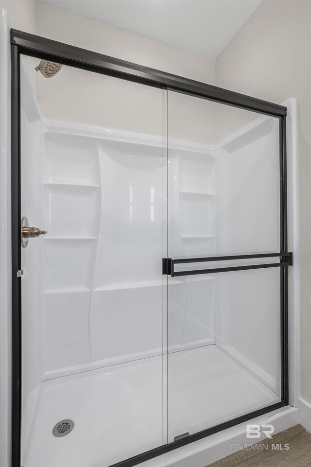 bathroom with wood-type flooring and a shower with shower door