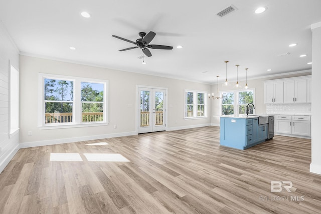 kitchen with crown molding, white cabinets, decorative light fixtures, and light wood-type flooring