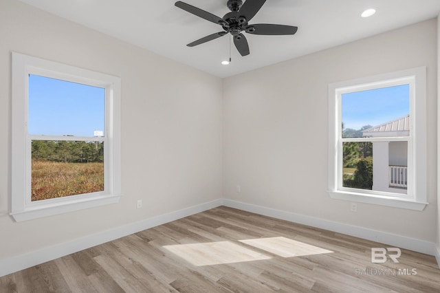 empty room with ceiling fan, a wealth of natural light, and light hardwood / wood-style floors