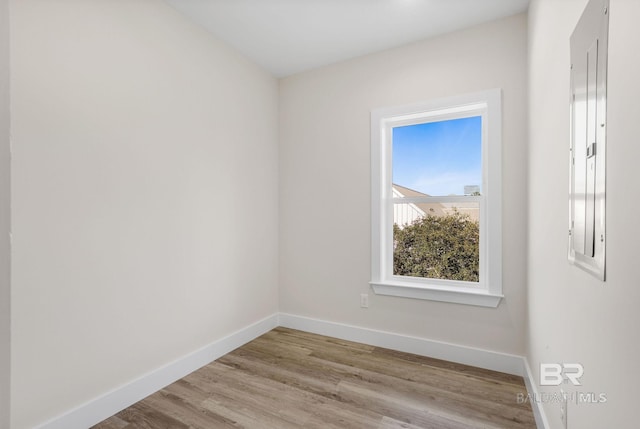 spare room featuring electric panel and light hardwood / wood-style floors