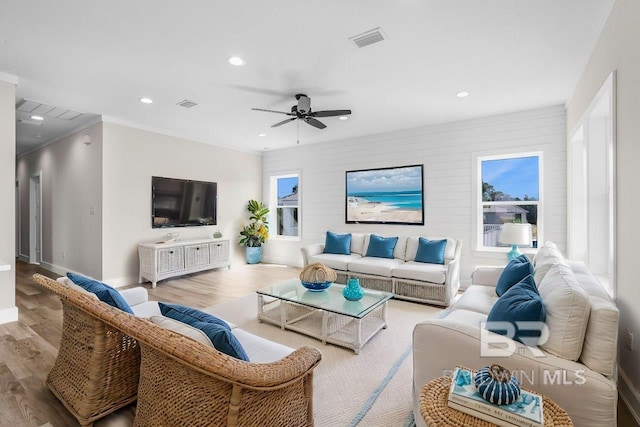 living room featuring light hardwood / wood-style floors, ornamental molding, and ceiling fan