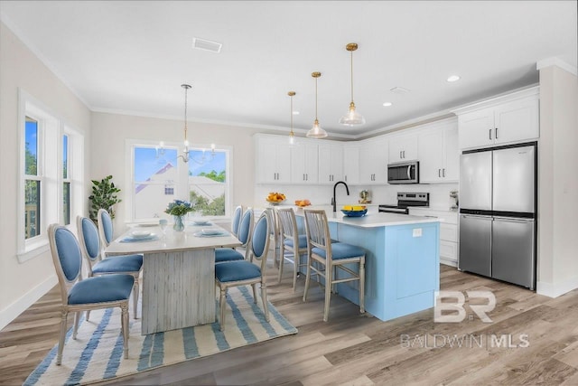 kitchen with a kitchen breakfast bar, a kitchen island with sink, stainless steel appliances, and white cabinets