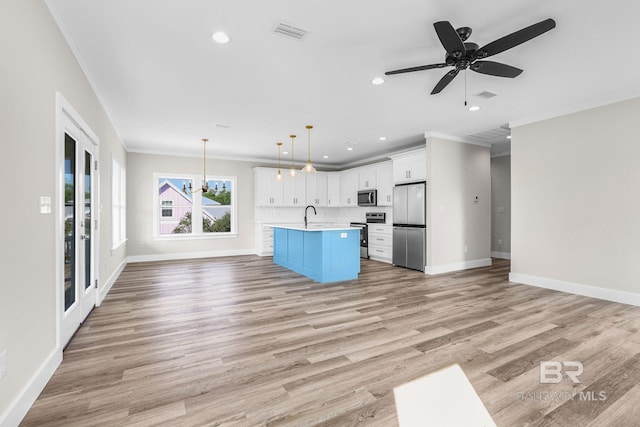 kitchen with white cabinets, appliances with stainless steel finishes, hanging light fixtures, and light hardwood / wood-style flooring