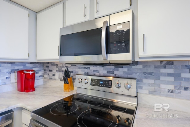 kitchen with white cabinets, backsplash, and stainless steel appliances