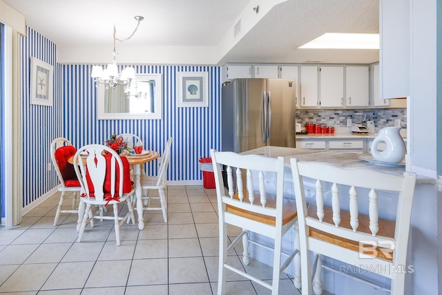 dining room with light tile patterned floors, baseboards, visible vents, wallpapered walls, and a notable chandelier