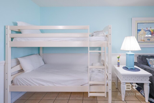 bedroom with tile patterned floors and wainscoting