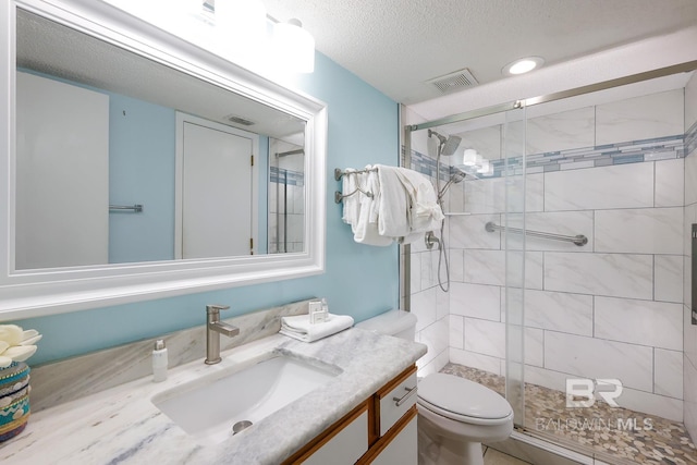 full bath with vanity, visible vents, a stall shower, a textured ceiling, and toilet
