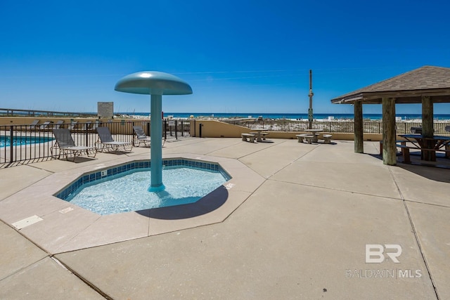 community pool with a patio area, fence, and a water view