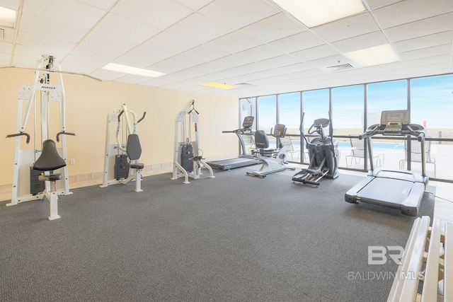workout area with a paneled ceiling, visible vents, and expansive windows
