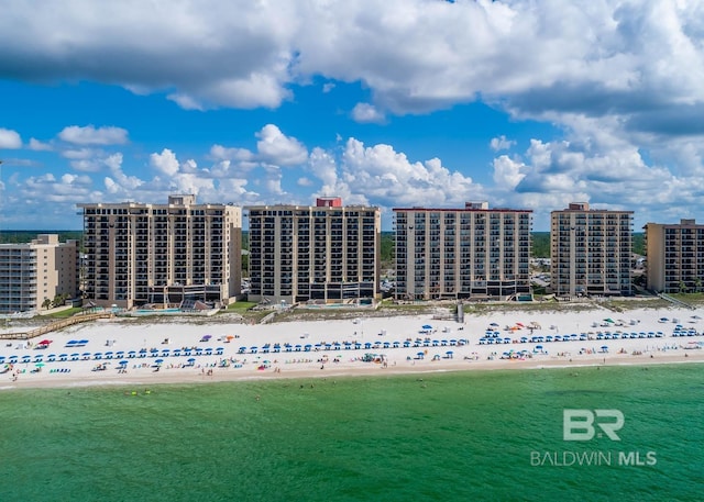 drone / aerial view featuring a water view, a city view, and a beach view