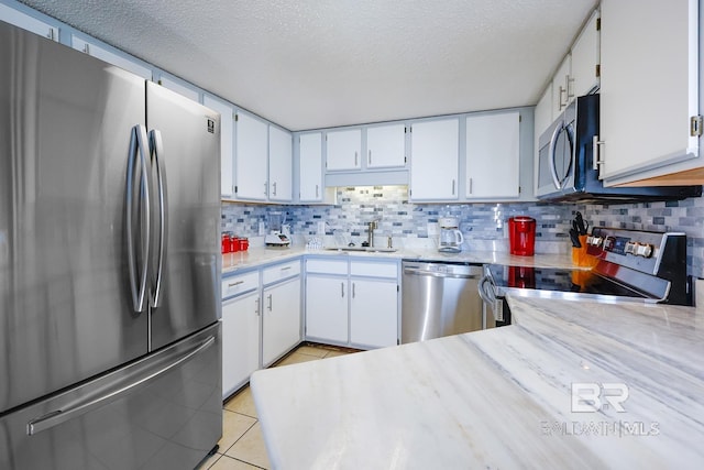 kitchen featuring light tile patterned flooring, tasteful backsplash, appliances with stainless steel finishes, and a sink