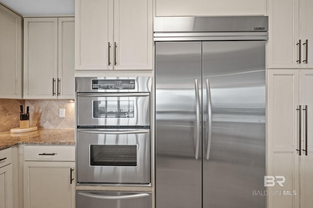 28107 Perdido Beach Blvd Unit D914, Orange Beach, AL 36561 - kitchen with white cabinets, stainless steel appliances, tasteful backsplash, light stone counters, and a warming drawer