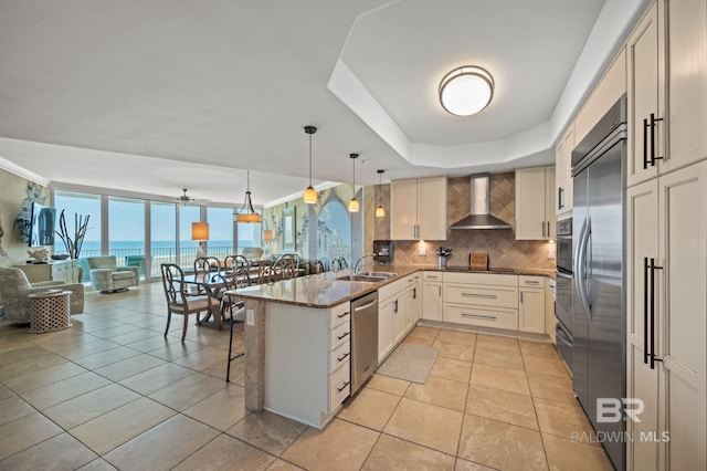 28107 Perdido Beach Blvd Unit D914, Orange Beach, AL 36561 - kitchen with a sink, wall chimney exhaust hood, a peninsula, stainless steel appliances, and decorative backsplash