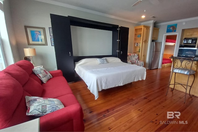 bedroom featuring ceiling fan, ornamental molding, wood finished floors, and freestanding refrigerator