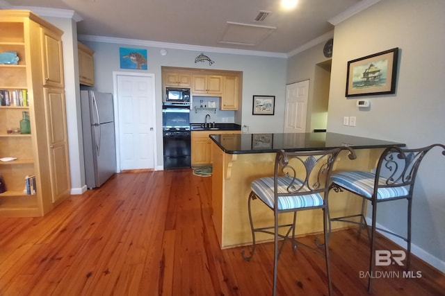 kitchen featuring wood finished floors, freestanding refrigerator, a peninsula, black microwave, and a sink