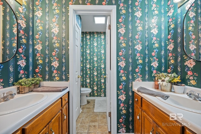 bathroom with vanity, toilet, and wallpapered walls