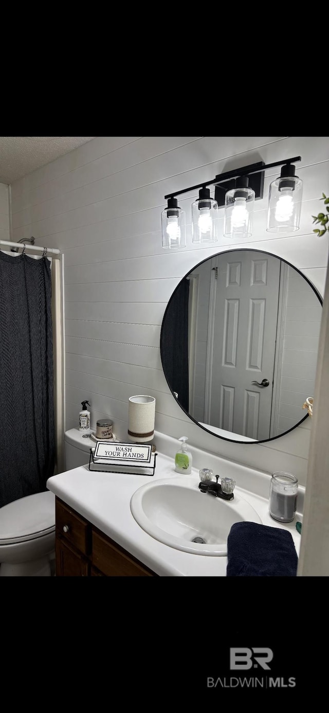 bathroom with curtained shower, vanity, and toilet