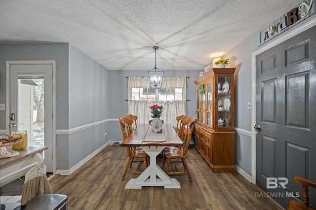 dining area featuring baseboards, a textured ceiling, a chandelier, and wood finished floors