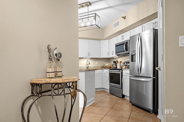 kitchen featuring stainless steel appliances, white cabinets, light stone counters, and light tile patterned floors