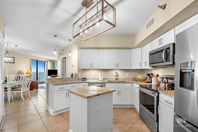 kitchen featuring a kitchen island, stainless steel appliances, sink, pendant lighting, and white cabinetry